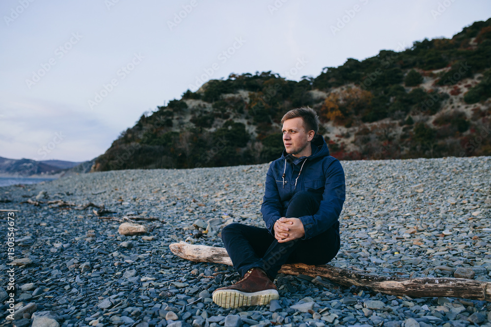 close up of man sitting on the beach and looking forward
