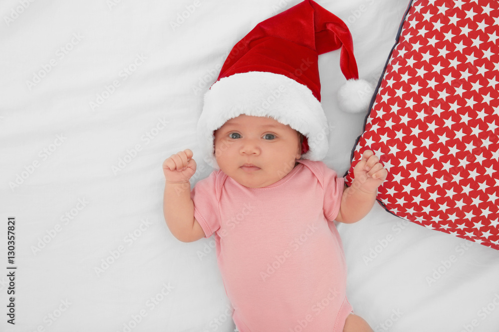 Cute baby in Santa hat on bed, top view Cute baby in Santa hat on bed, top view