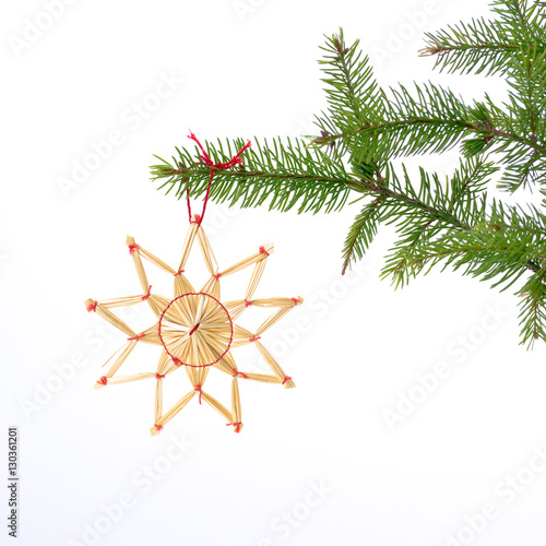 halm stjärna hänger i julgran med vit bakgrund
