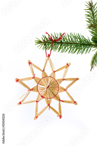 juldekoration halm stjärna som hänger i grankvist med vit bakgrund