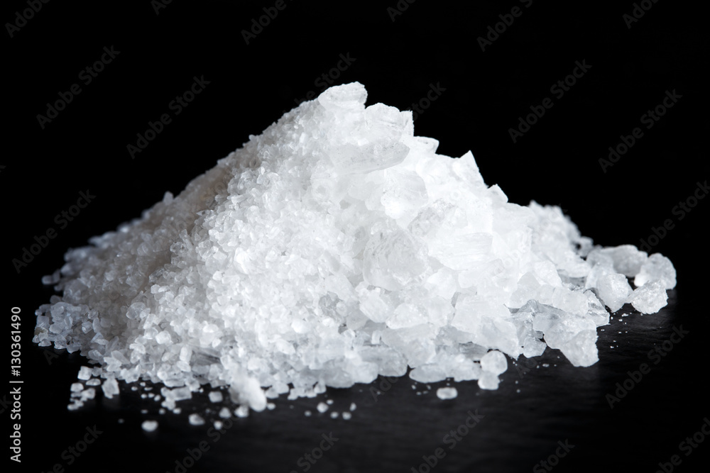 Heap of fine and coarse salt isolated on black.