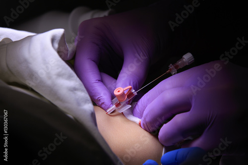 Anesthesiologist inserts the catheter into the leg of a child closeup © vzmaze