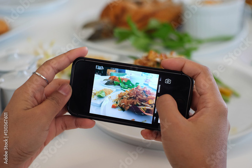 Using hands to take food's picture by smart phone.