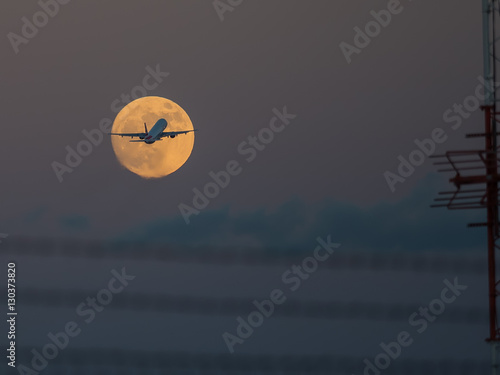 A plane taking off appears to divide the moon