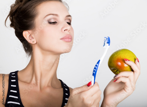Portrait of young woman holding an apple and toothbrush  dental health concept