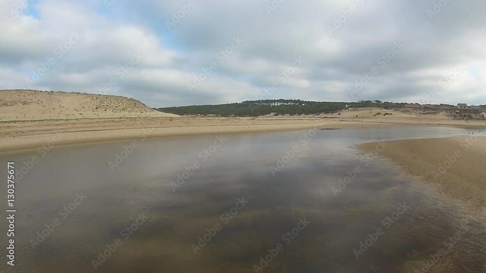 Survol d'une plage atlantique avec une dune et une rivière par un temps couvert Survol d'une plage atlantique avec une dune et une rivière par un temps couvert