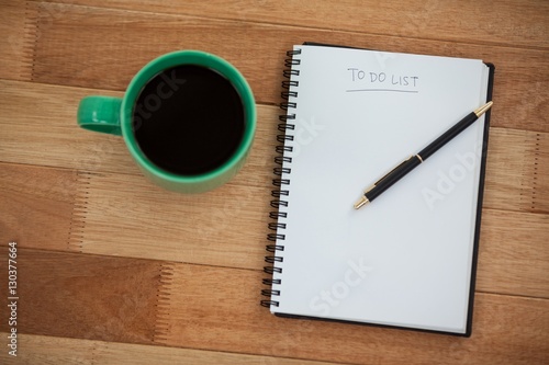 Close-up of coffee mug with diary and pen