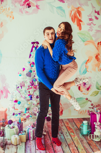 Strong man in blue sweater holds tiny lady on his arms standing © pyrozenko13