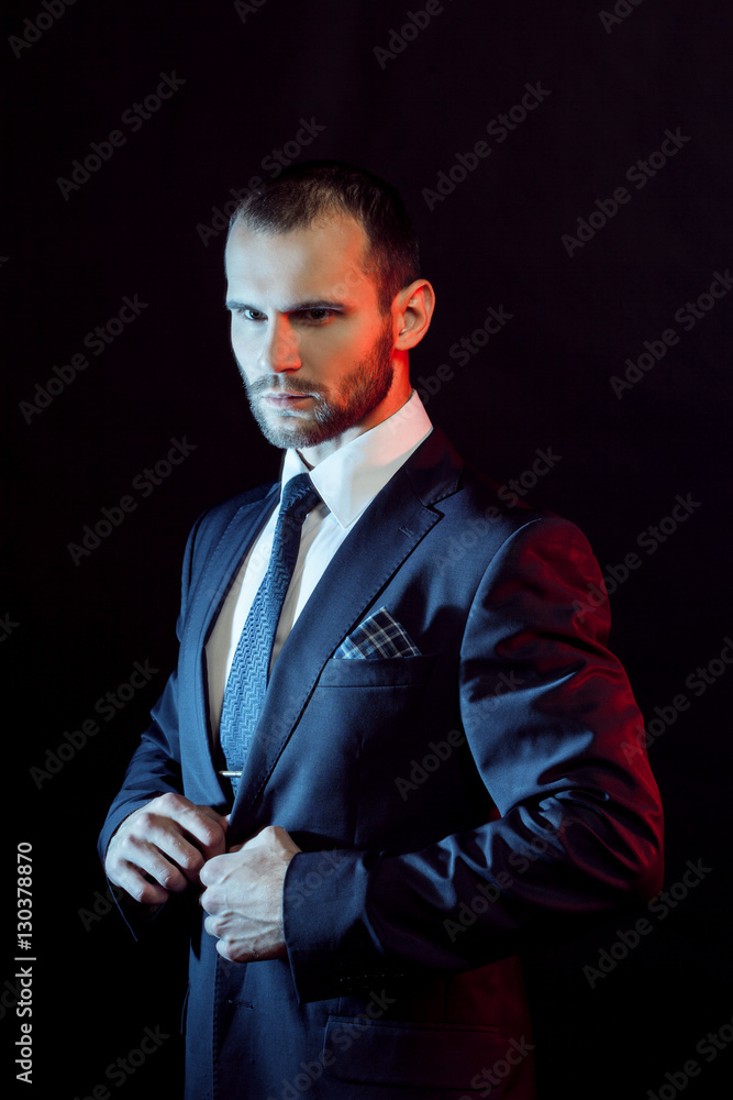 Obraz premium serious man in a business suit, dark background, backlight blue and red tones