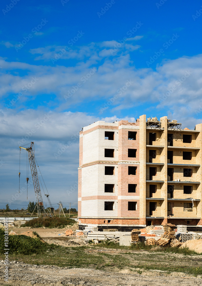 Building crane and apartment house under construction against sky Building crane and apartment house under construction against sky
