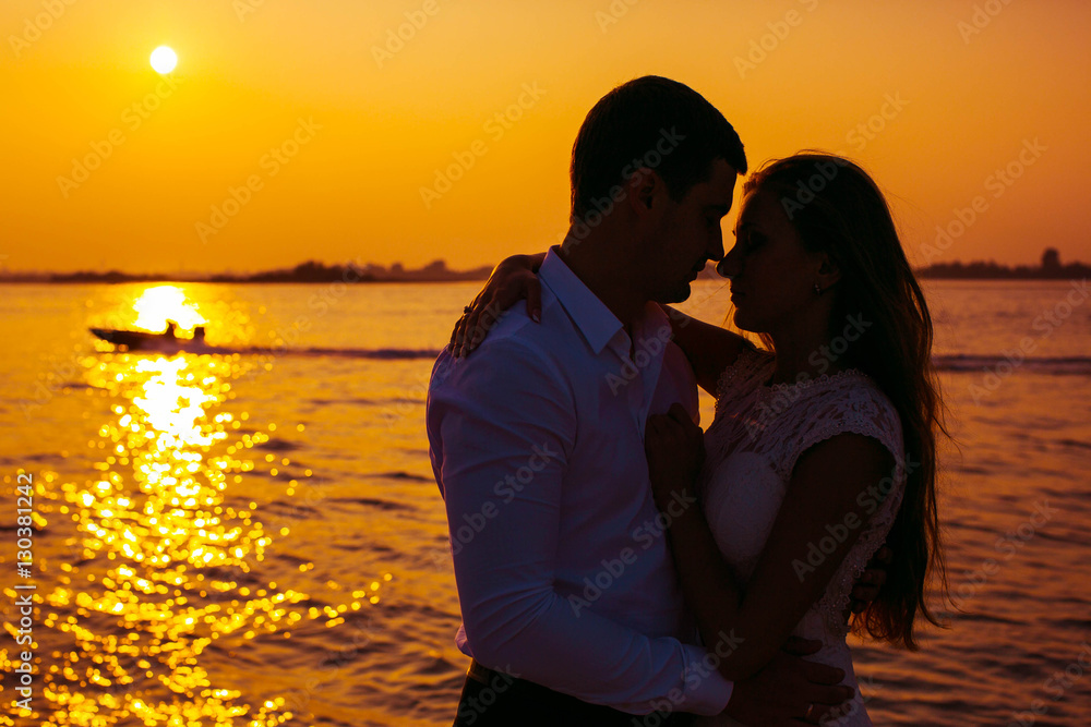 beautiful and young man and woman hug each other on the sunset