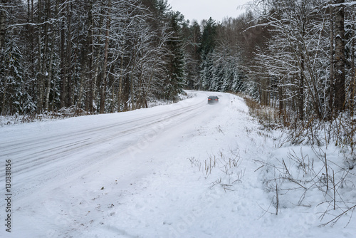 car traveling on snowy forest road between the trees