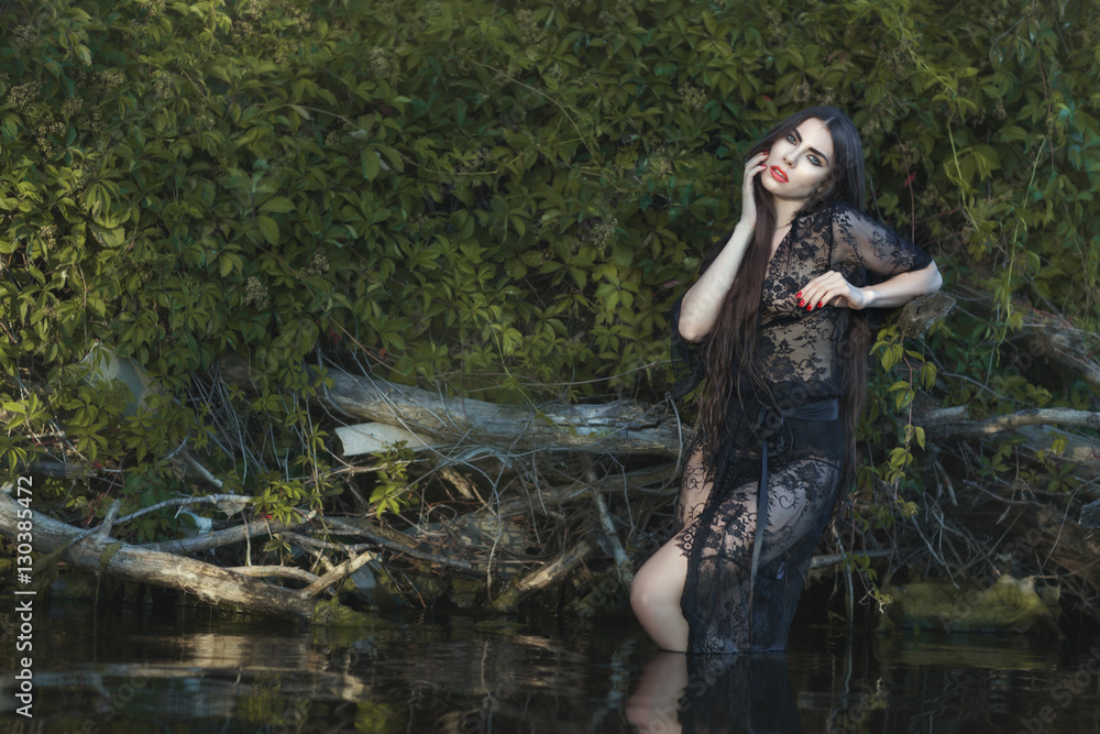 Beautiful woman in the water in nature, she is dressed in a peignoir.
