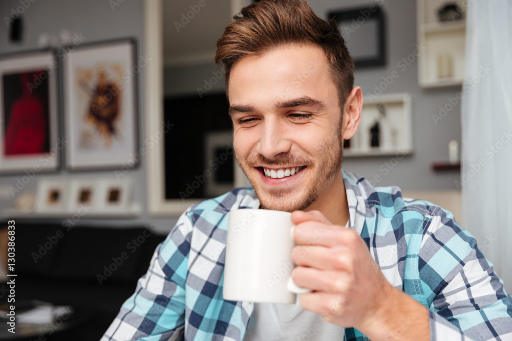 Cheerful handsome young man holding cup of tea. Cheerful handsome young man holding cup of tea.
