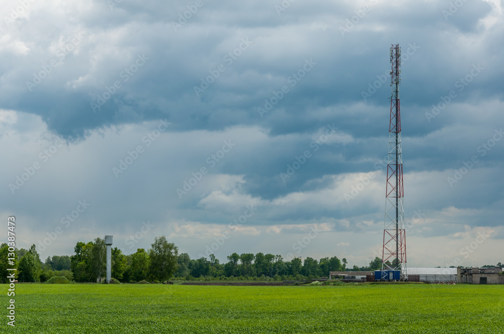 tower of mobile communication and telecommunication in rural areas against the background of the cloudy sky