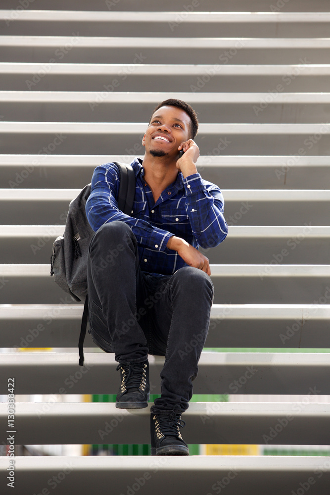 happy man sitting on steps talking on mobile phone happy man sitting on steps talking on mobile phone