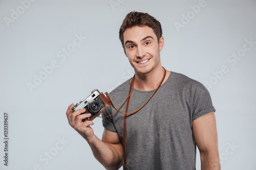 Portrait of a smiling casual man holding retro camera