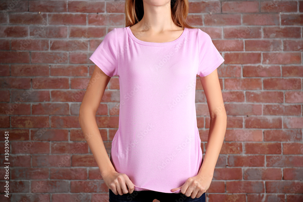 Young woman in blank color t-shirt standing against brick wall, close up Young woman in blank color t-shirt standing against brick wall, close up