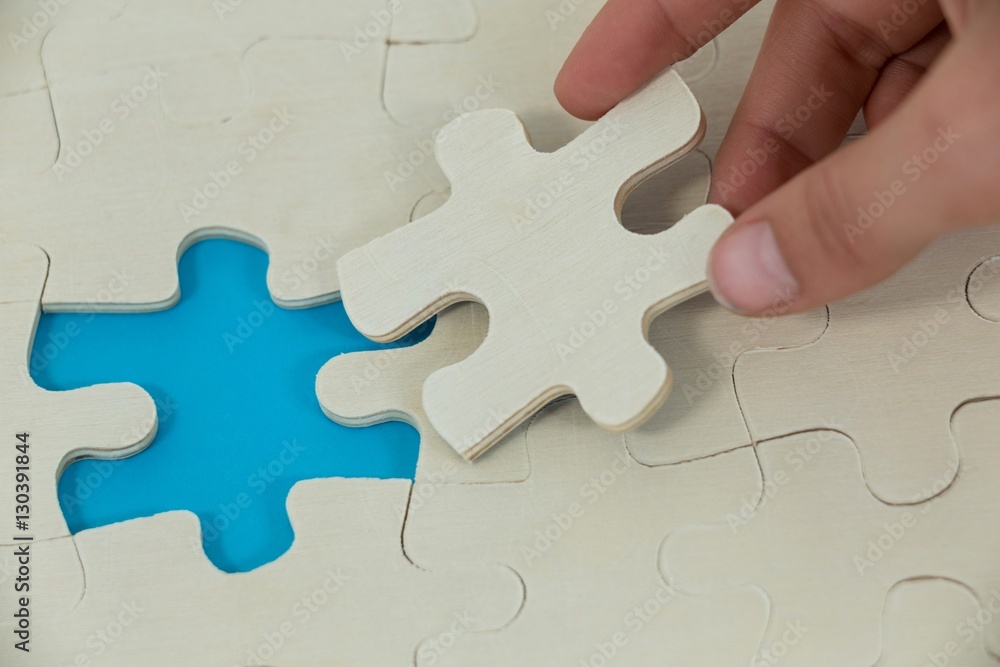 Woman placing missing piece in jigsaw puzzle Woman placing missing piece in jigsaw puzzle