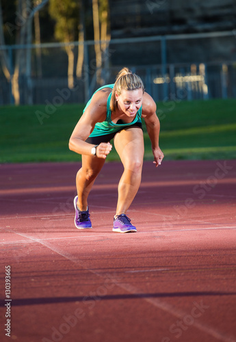 Female fitness athlete setting of on a race on a tartan athletics track