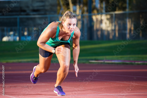 Female fitness athlete setting of on a race on a tartan athletics track