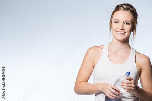Female fitness model with water bottle on white background.