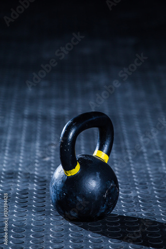 Fototapeta Naklejka Na Ścianę i Meble -  Kettle bell weight in a dark gym with moody and edgy lighting