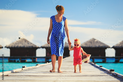 mother and little daughter walking on beach resort