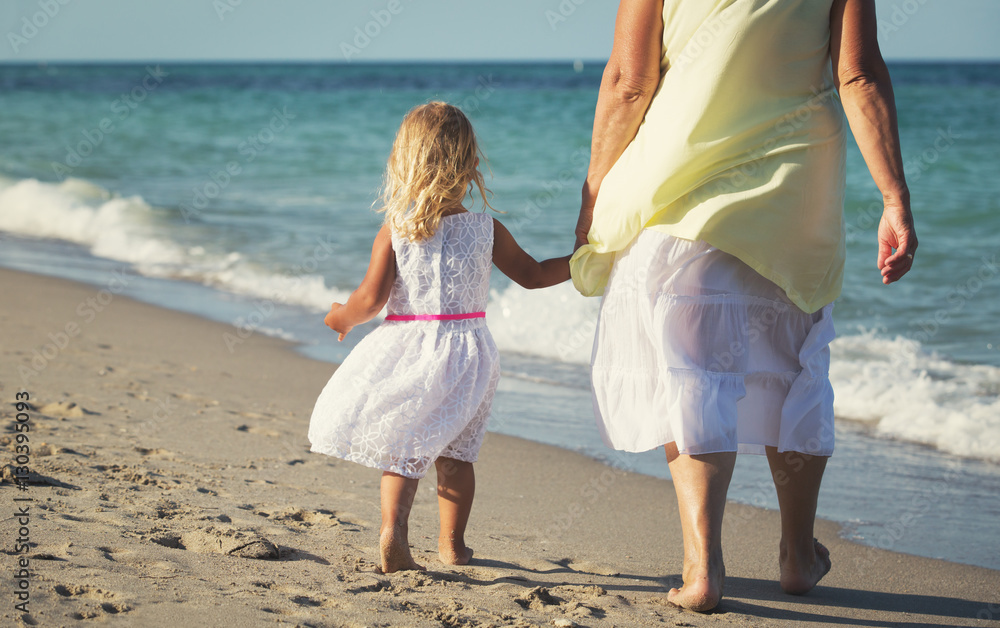 Happy grandmother with little girl walk at beach