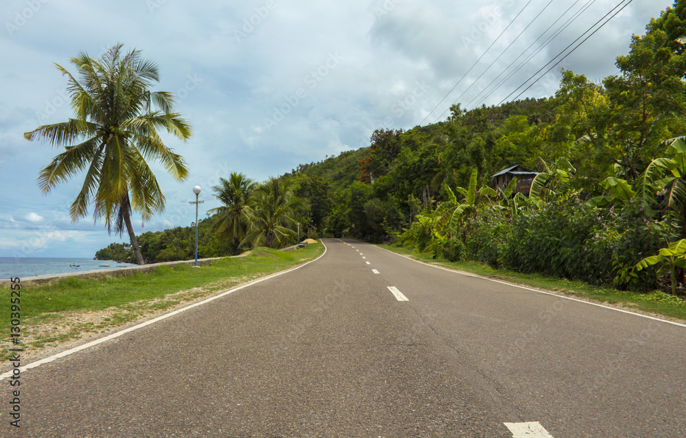 Highway on tropical island. Coastal road in the afternoon. Empty road by the seaside.