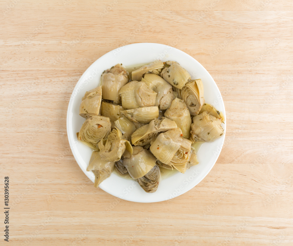 Marinated artichoke hearts on a plate atop a wood table top view. Marinated artichoke hearts on a plate atop a wood table top view.