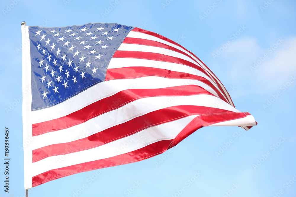 Fototapeta premium Ruffled American flag on blue sky background