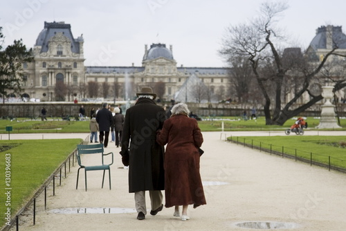 Elderly couple take a calm stroll arm in arm through Jardin des Tuileries by the Louvre Museum art gallery, Central Paris, France photo