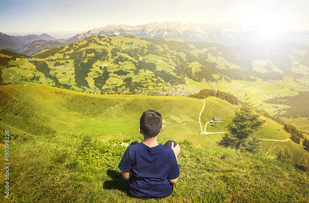 Young boy admiring the nature from the peak of the mountain Young boy admiring the nature from the peak of the mountain