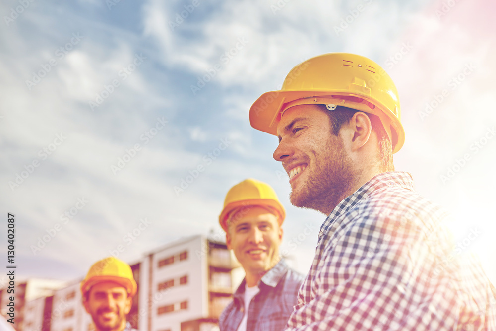 group of smiling builders in hardhats outdoors group of smiling builders in hardhats outdoors