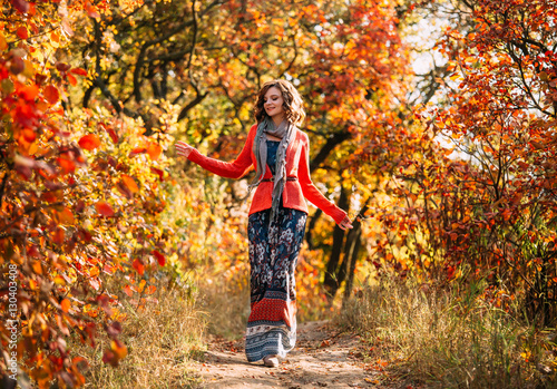 Luxurious lady in colorful dress.A nice smile, playful gait.Curly hair.Beautiful a scarf wraps her neck it.Golden autumnal.Picturesque nature.Fantastic shooting.Fashionable toning.Creative color. © kharchenkoirina