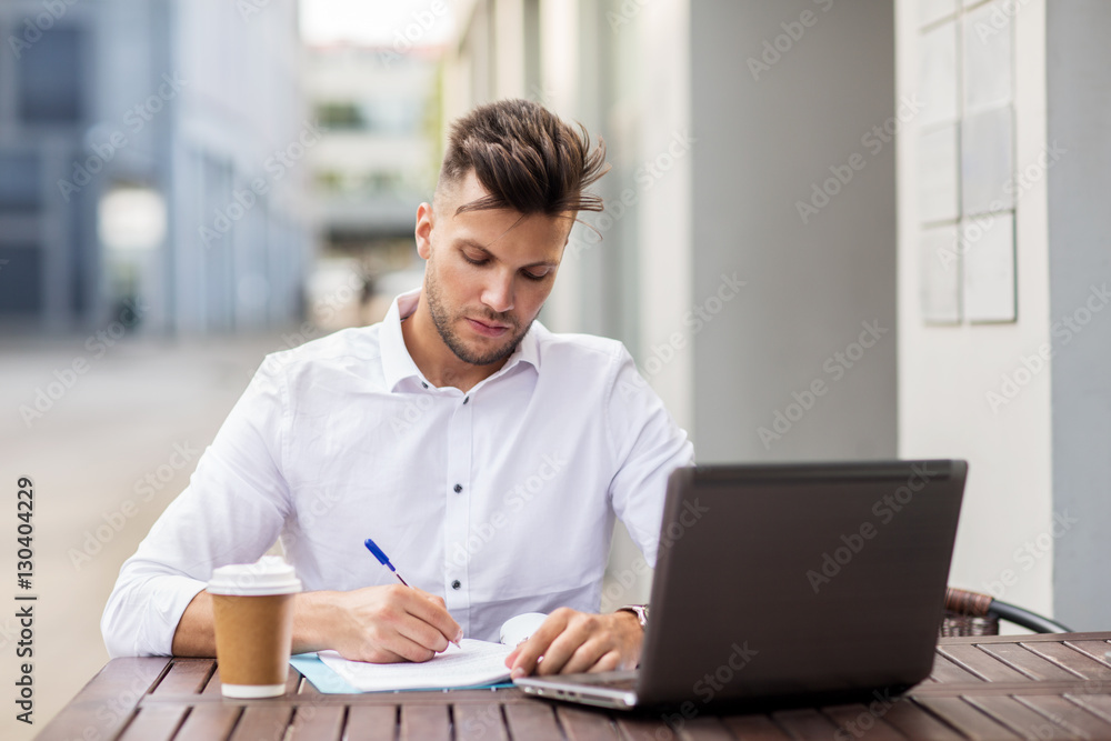man with laptop and coffee at city cafe
