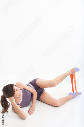 femme sportive couchée qui fait des exercices avec un élastique