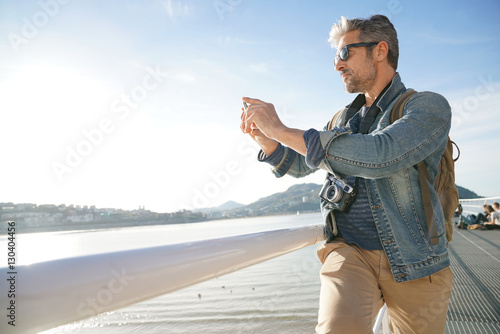 Man standing by the sea using smartphone, winter season