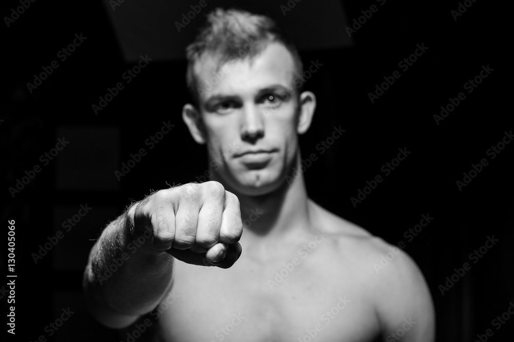 Male fitness model showing muscles in studio with a black backgr Male fitness model showing muscles in studio with a black backgr
