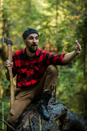 portrait of a man - lumberjack with an ax in the forest, front view