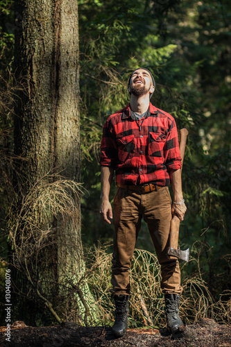 portrait of a man - lumberjack with an ax in the forest, front view