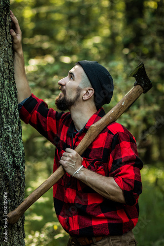 portrait of a man - lumberjack with an ax in the forest, side view