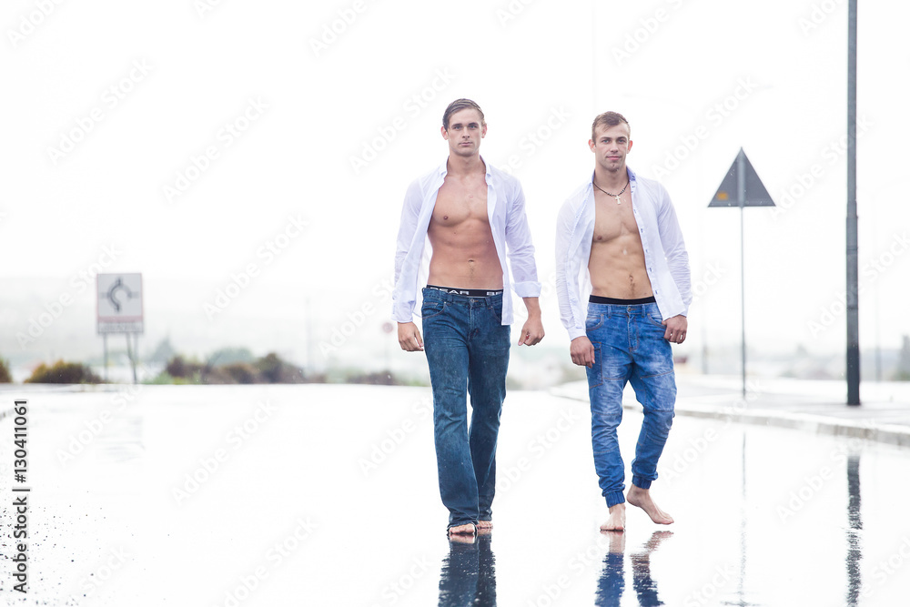 Two Good looking male models walking in a streat in the pouring