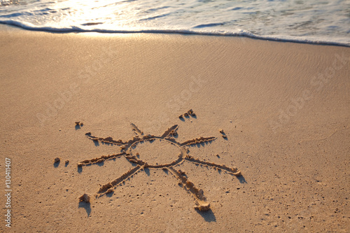 petit soleil dessiné sur le sable à la mer