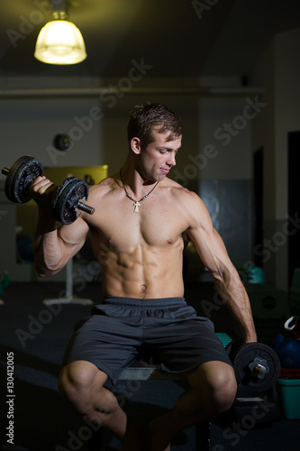 A Good looking male model flexing his muscles in a gym using wei