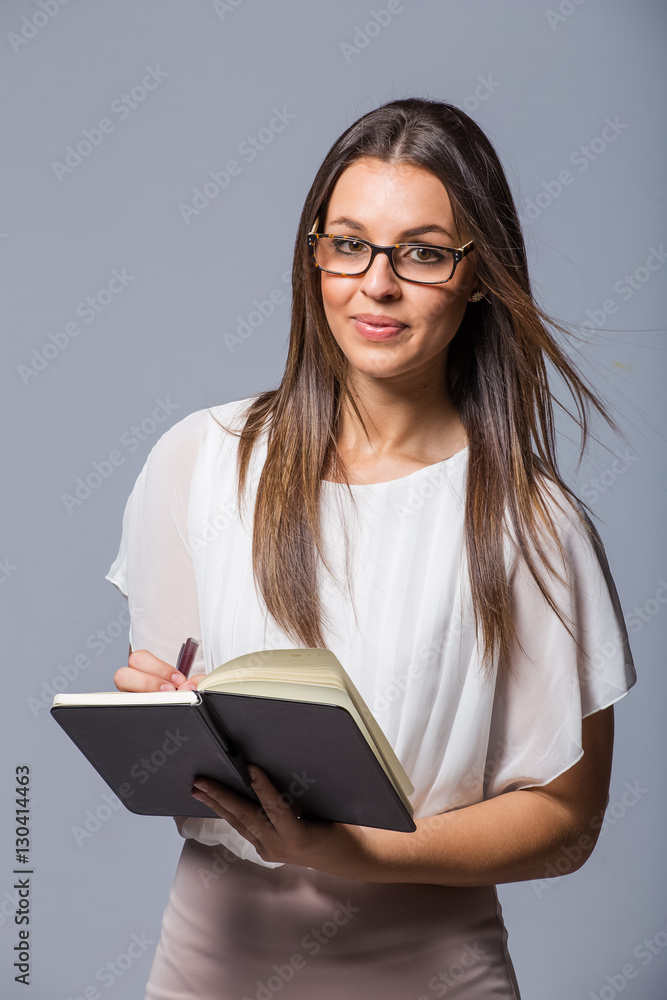Pretty business woman holding a day planner book / dairy in a studio on plain background Pretty business woman holding a day planner book / dairy in a studio on plain background