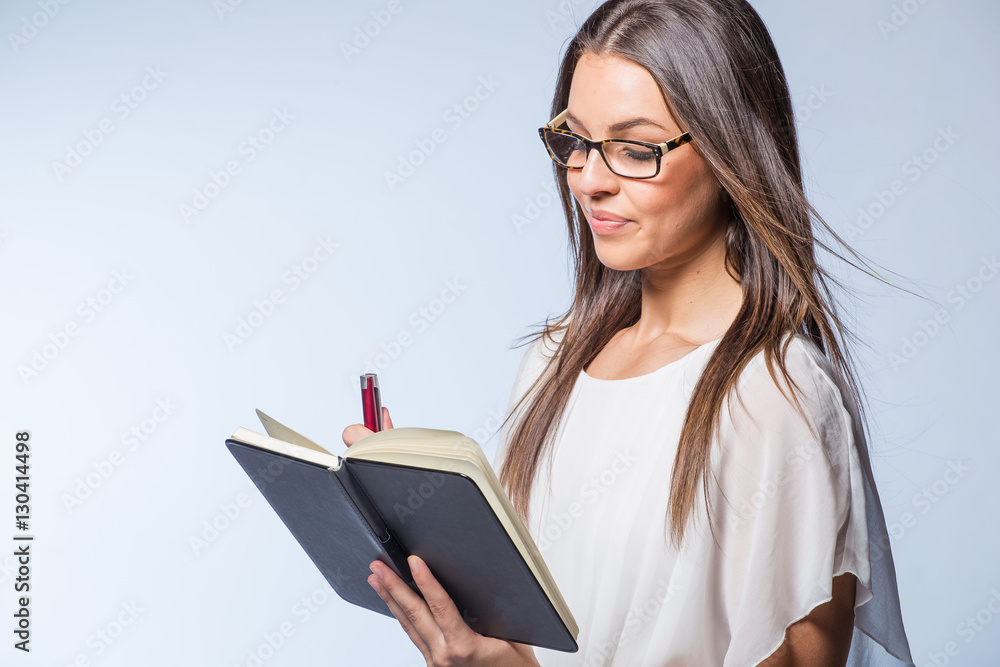 Pretty business woman holding a day planner book / dairy in a studio on plain background Pretty business woman holding a day planner book / dairy in a studio on plain background