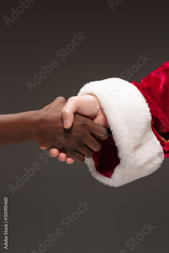 The handshake of Santa Claus hand and hand of african man
