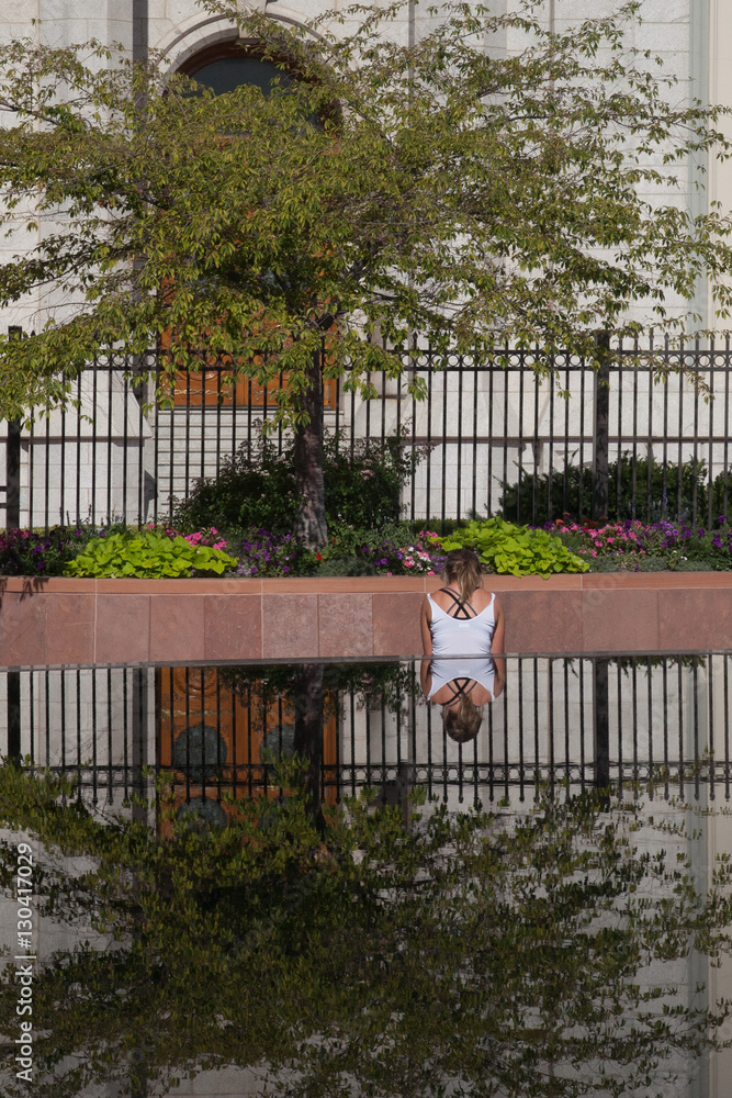 Girl sitting under tree are reflected on pond in foreground of photo. Girl sitting under tree are reflected on pond in foreground of photo.